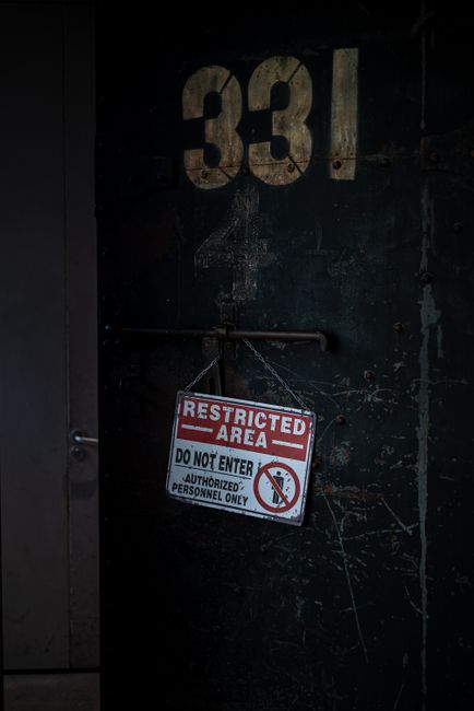 A dark, industrial-style door marked with the number 331 in large, faded beige paint, featuring a metal handle and a chain securing a rectangular red and white sign that reads 'RESTRICTED AREA. DO NOT ENTER. AUTHORIZED PERSONNEL ONLY.' The door surface shows signs of wear, with visible scratches and peeling paint. The scene suggests a secure or private zone, possibly within a building or facility. This image relates to house removals and moving services by illustrating controlled access areas that may be encountered during logistical operations by companies such as Man with Van Totteridge, who specialise in professional home relocation, furniture transport, and packing and moving processes.